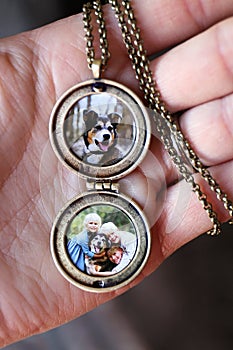 Woman`s Hand Holding Antique Locket with Photos of Children and Pet Dog Inside