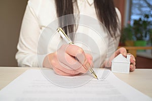 Woman`s hand holding ballpoint pen writing on agreement contract  paper sheet, applying for mortgage loan, filling in document tem