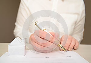 Woman`s hand holding ballpoint pen writing on agreement contract  paper sheet, applying for mortgage loan, filling in document tem