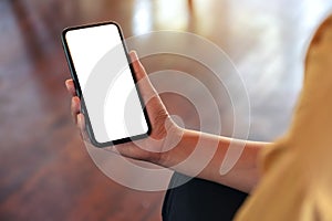 A woman`s hand holding black mobile phone with blank white desktop screen