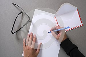 Woman`s hand holding blue pen ready to write on blank paper on a desk