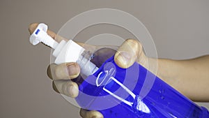 Woman`s hand  holding bottle of blue alcohol gel. Health care concept