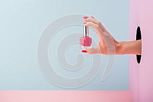 Woman`s hand holding a bottle of pink nail polish