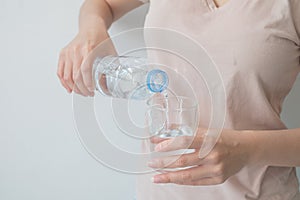 Woman`s hand holding a bottle of water Pouring water into a glass