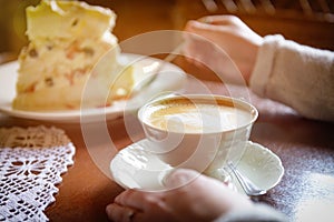 Woman`s hand holding cappuccino cup in the cafe