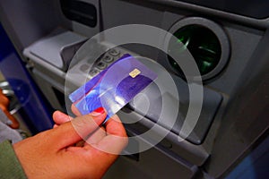 A Woman's Hand Is Holding A Card For A Transaction At An Atm Machine