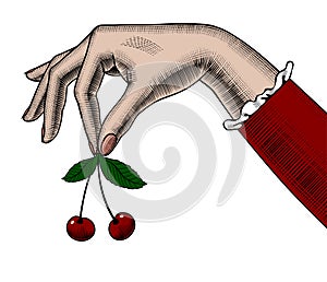 Woman`s hand holding cherries in her fingers