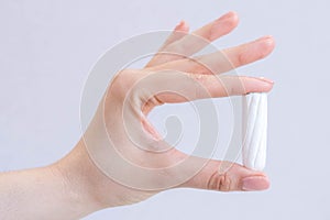 Woman`s hand holding clean cotton tampon close-up. Young woman preparing menstruation time. Soft tender protection woman