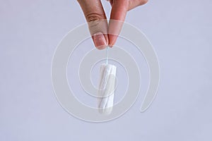 Woman`s hand holding clean cotton tampon close-up. Young woman preparing menstruation time. Soft tender protection woman