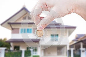 Woman`s Hand holding Coin on house background