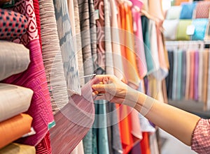 woman's hand holding color samples of fabric in interior design store