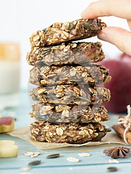 Woman`s hand holding a cookie from a stack of apple oatmeal breakfast cookies