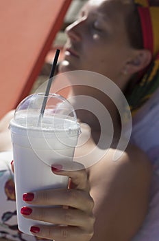 Woman`s hand holding a cup of Greek frappe with drinking straw