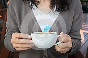 Woman`s hand holding a cup of redolent cappuccino coffee.