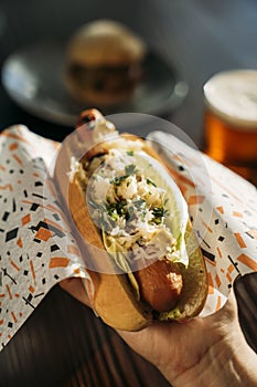 Woman`s hand holding a delicious vegan carrot dog