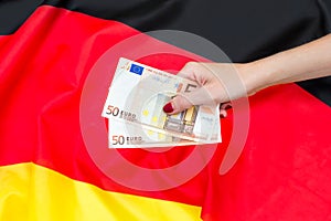 Woman's hand holding euro bills against german flag
