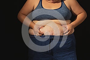 Woman& x27;s hand holding excessive belly fat