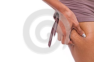 Woman's hand holding excessive leg fat or cellulite, isolated