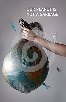 A woman`s hand holding a garbage bag with a globe of planet Earth.The inscription OUR PLANET IS NOT A GARBAGE. Concept of