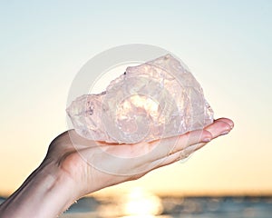 Woman`s hand holding gem grade rough Rose Quartz chunk from Madagascar