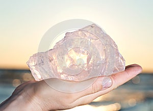 Woman`s hand holding gem grade rough Rose Quartz chunk from Madagascar