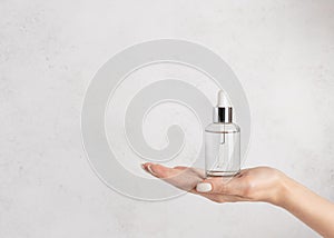 Woman`s hand holding a glass bottle with moisturizing serum. Beauty cosmetic skincare concept