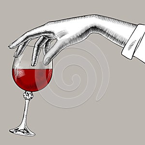 Woman`s hand holding a glass with red wine photo