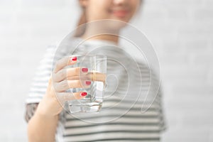 Woman`s of hand holding a glass of water on white background