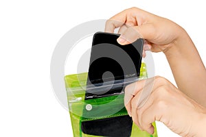 Woman`s hand holding the green waterproof bag and put mobile phone into the bag isolated on white background with clipping path.P