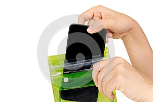Woman`s hand holding the green waterproof bag and put mobile phone into the bag isolated on white background with clipping path.P photo