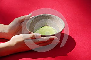 Woman's hand holding Japanese green tea bowl