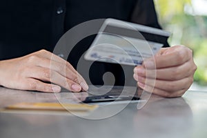 A woman`s hand holding and looking at credit cards on the table