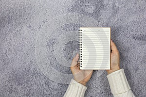 A woman`s hand holding a notebook on the desk.