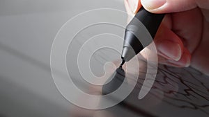 Woman's hand holding a pen stylus making an illustration using a digital drawing artist tablet. Close up macro shot