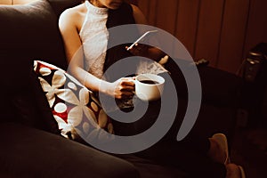 Woman's hand holding a phone and a cup of coffee. Technology and home concept.