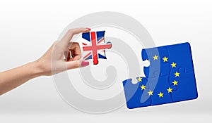 Woman's hand holding piece of jigsaw puzzle with European Union and Great Britain flag on white background