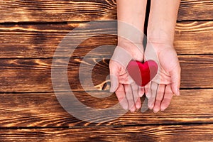 Woman& x27;s hand holding red heart on the old wooden background Concept Of Valentine& x27;s Day