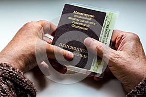 Woman`s hand holding russian pension certificate.