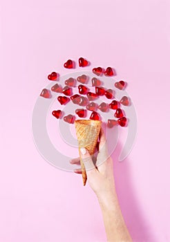 Woman`s hand holding a scoop of ice-cream. Heart shape drops all around imitating ice-cream.