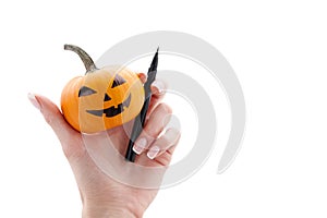 Woman`s hand holding small halloween pumpkin and marker pen