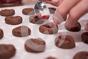 Woman`s Hand Holding A Spoon And Putting Cherry Jam In Chocolate Dough To Make Christmas Cookies