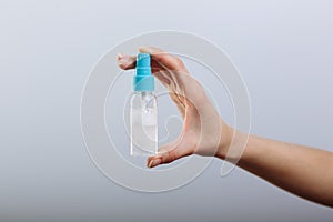 Woman& x27;s hand holding spray bottle sanitizer  on gray background