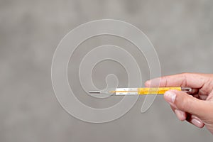 A woman`s hand holding a thermometer