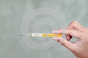 A woman`s hand holding a thermometer