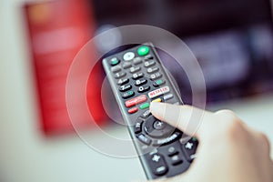 Woman`s hand is holding a TV remote control with streaming media services.