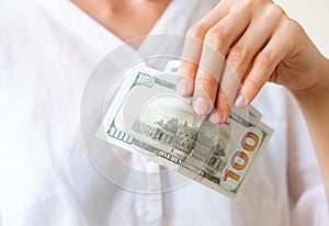 Woman`s hand is holding two hundreds of dollars