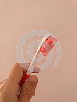 Woman's hand holding a used kids toothbrush red and white colors