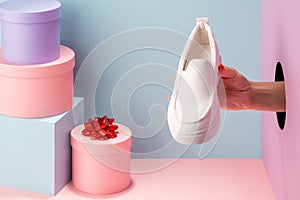 Woman`s hand holding a white loafer on blue background