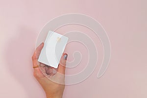 Woman`s hand holding white plastic credit or debit card with chip