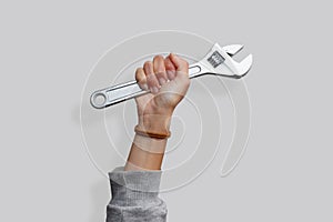 Woman's hand holding a wrench on an isolated white background